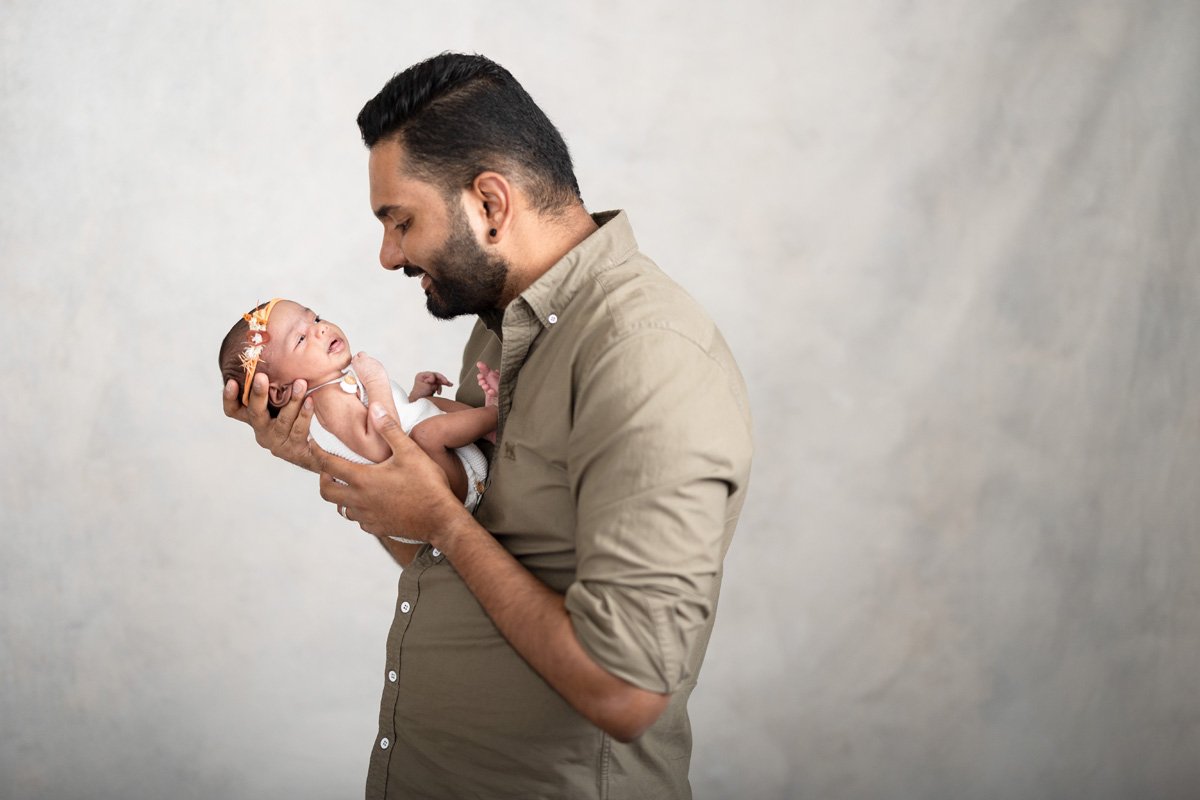 newborn baby girl in orange headband with dad